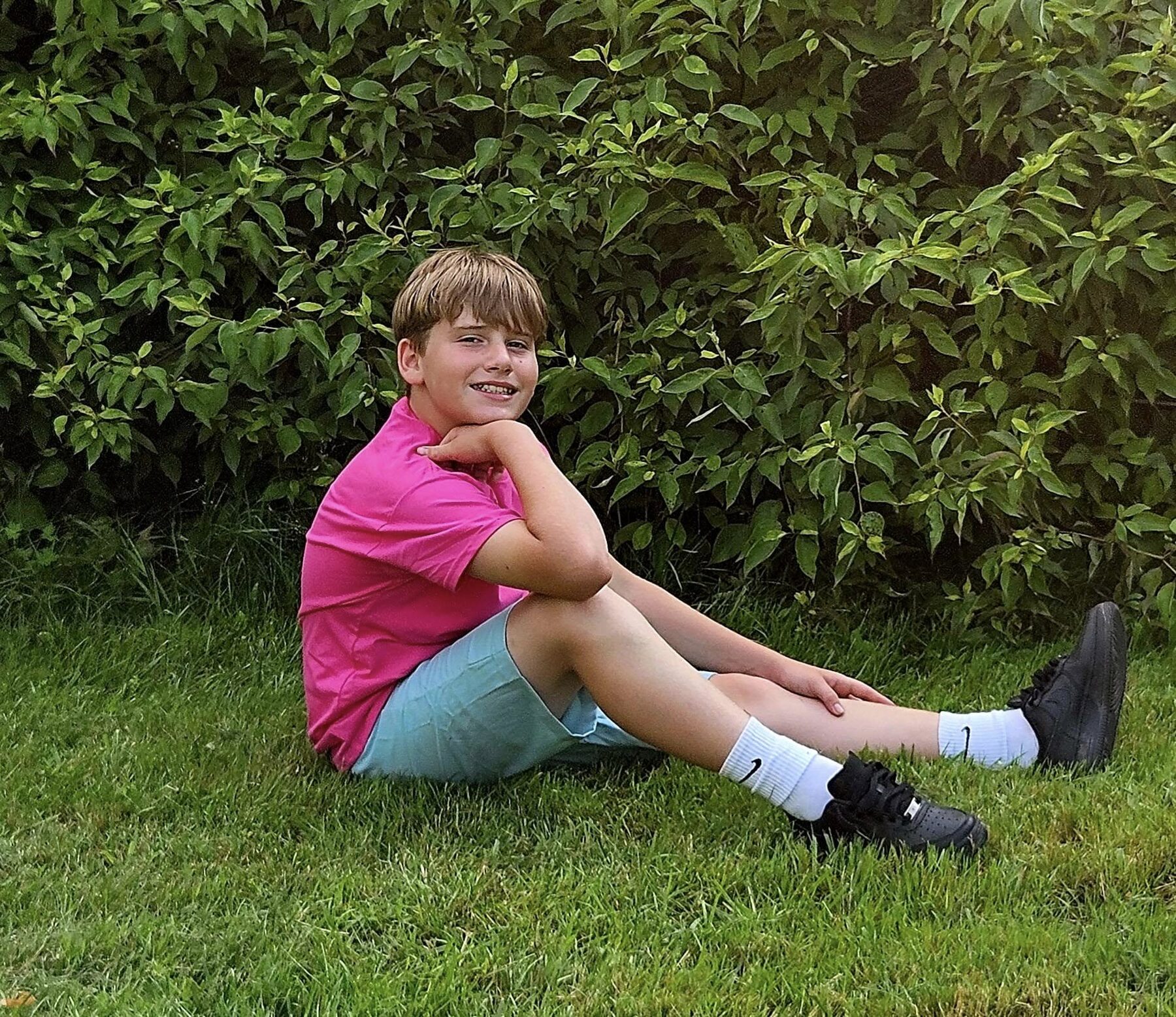 Relaxed portrait of a young boy seated in the grass