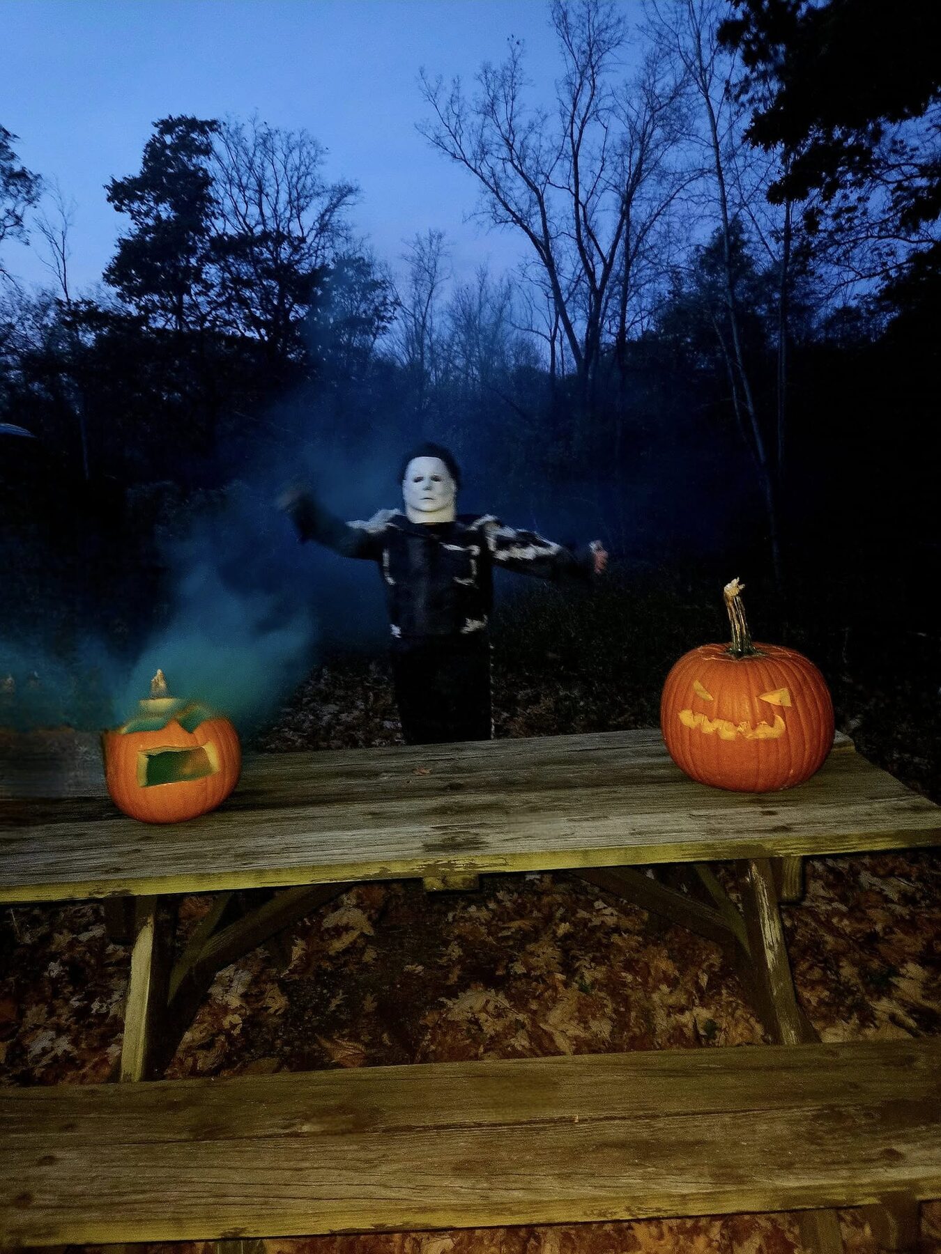 Halloween scene with lit pumpkins and evening fog