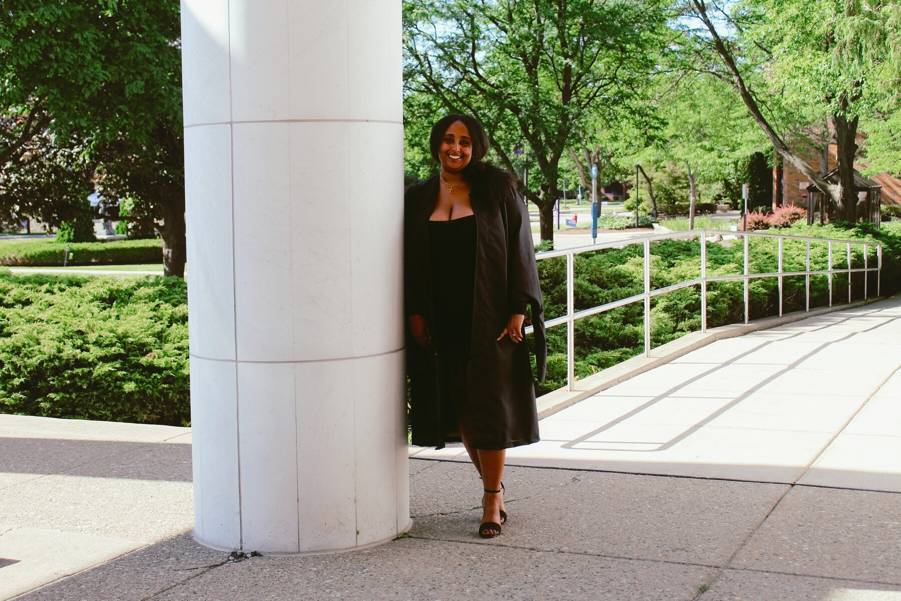 Graduate smiling in front of a classic columned building