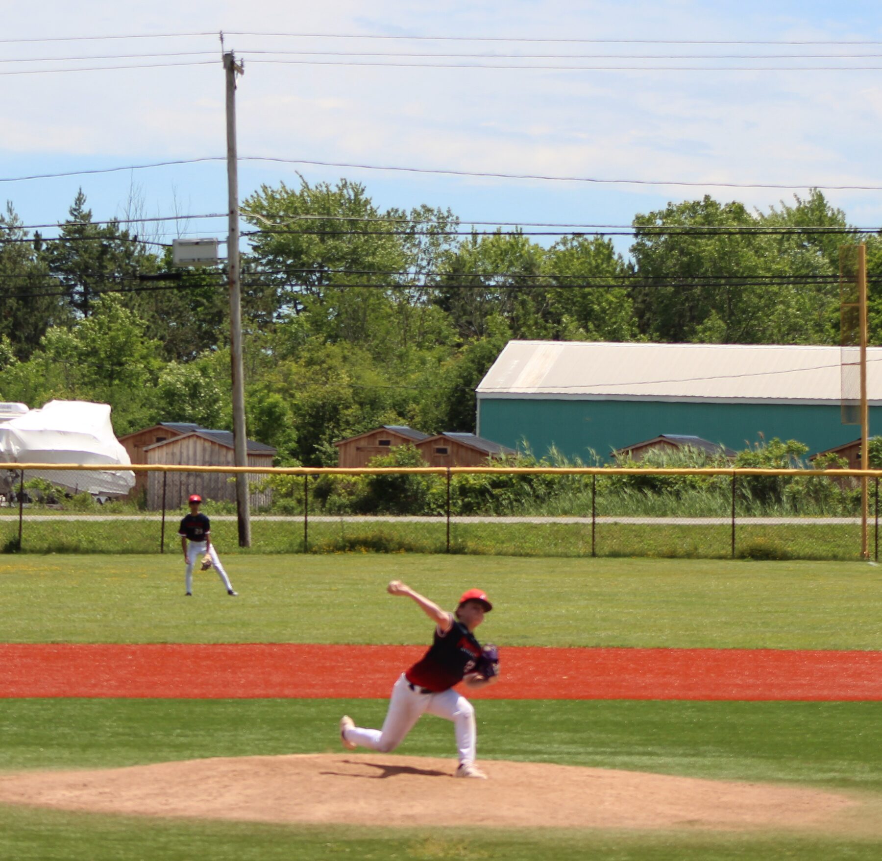 Young pitcher mid throw during an afternoon baseball game