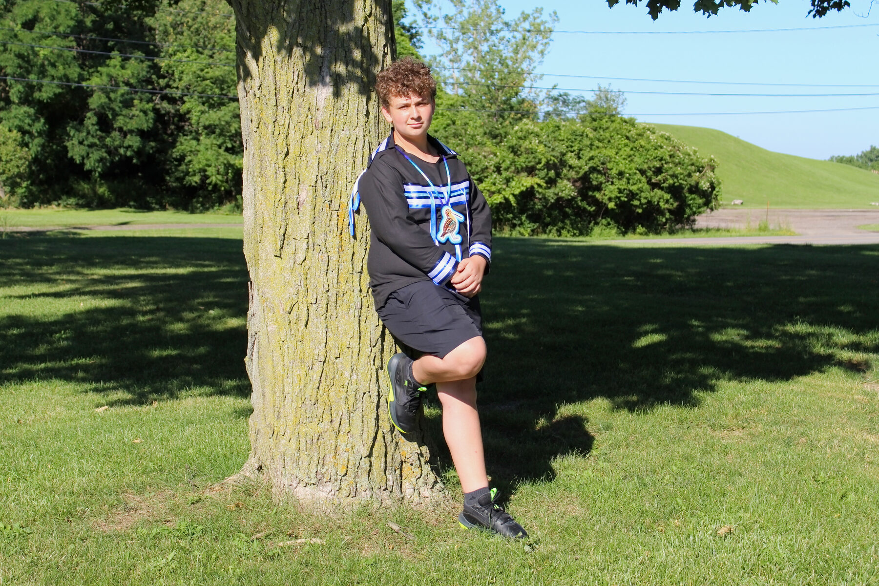 School milestone portrait leaning against a park tree